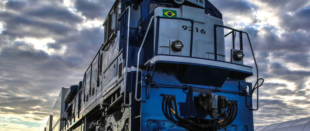 Locomotiva azul vista em ângulo baixo sob céu nublado.