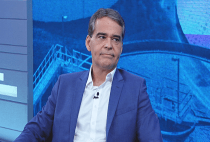 Homem de paletó azul  camisa branca, em entrevista